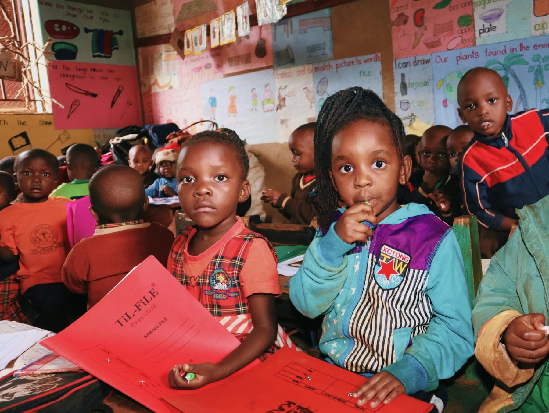 Preschool children gathered together with their classroom folders.